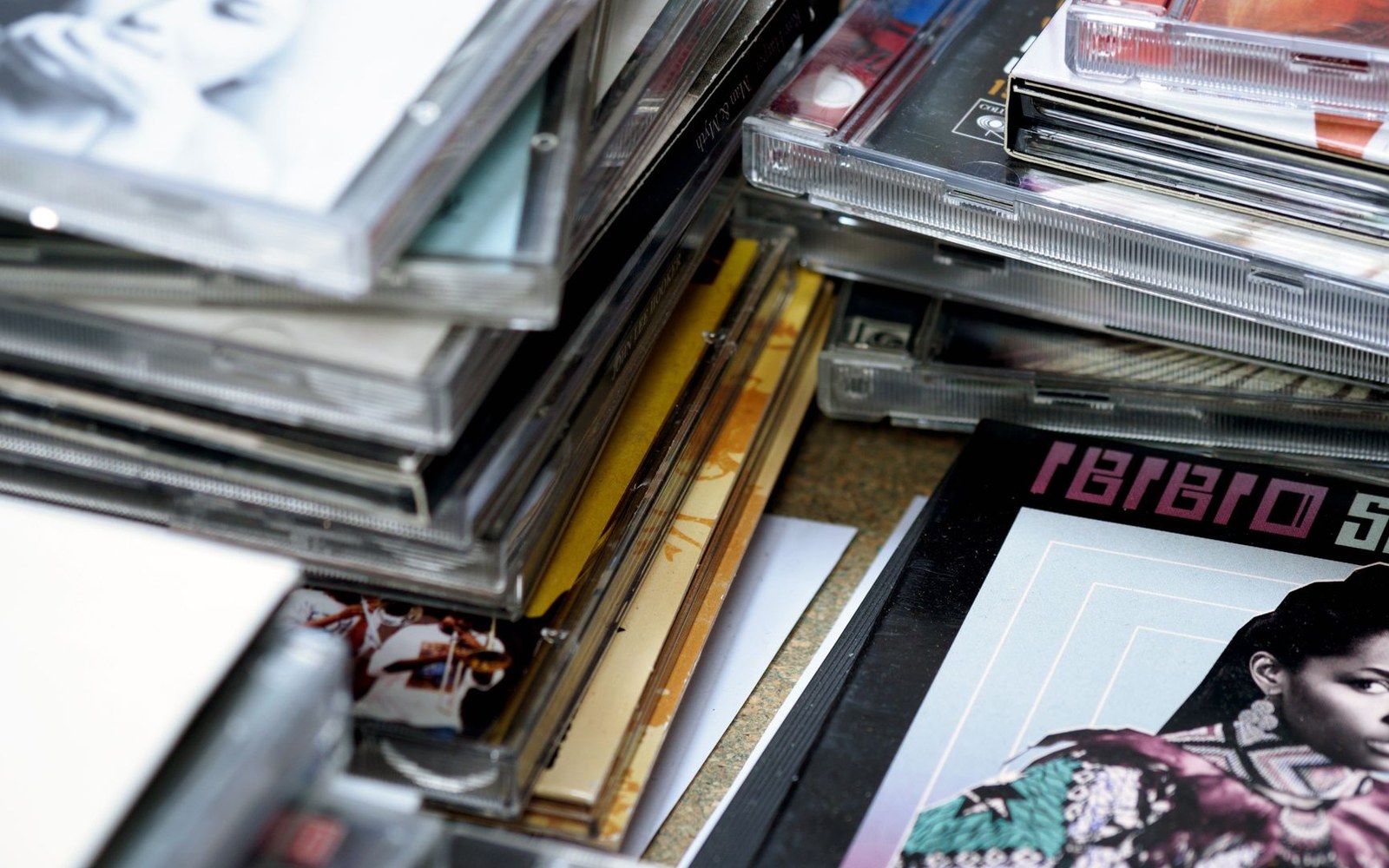 Stacks of jewel-cased cds piled together with album covers visible at the edges