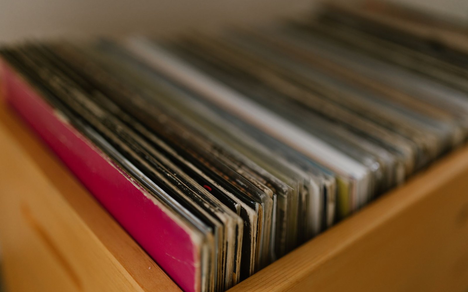 Rows of vinyl records stand upright in a wooden shelf compartment