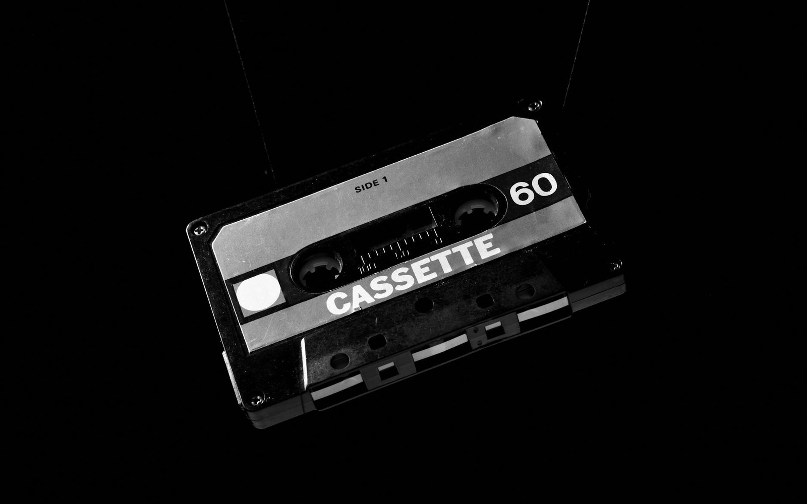 A 60-minute cassette tape labeled "Side 1" suspended against a black background