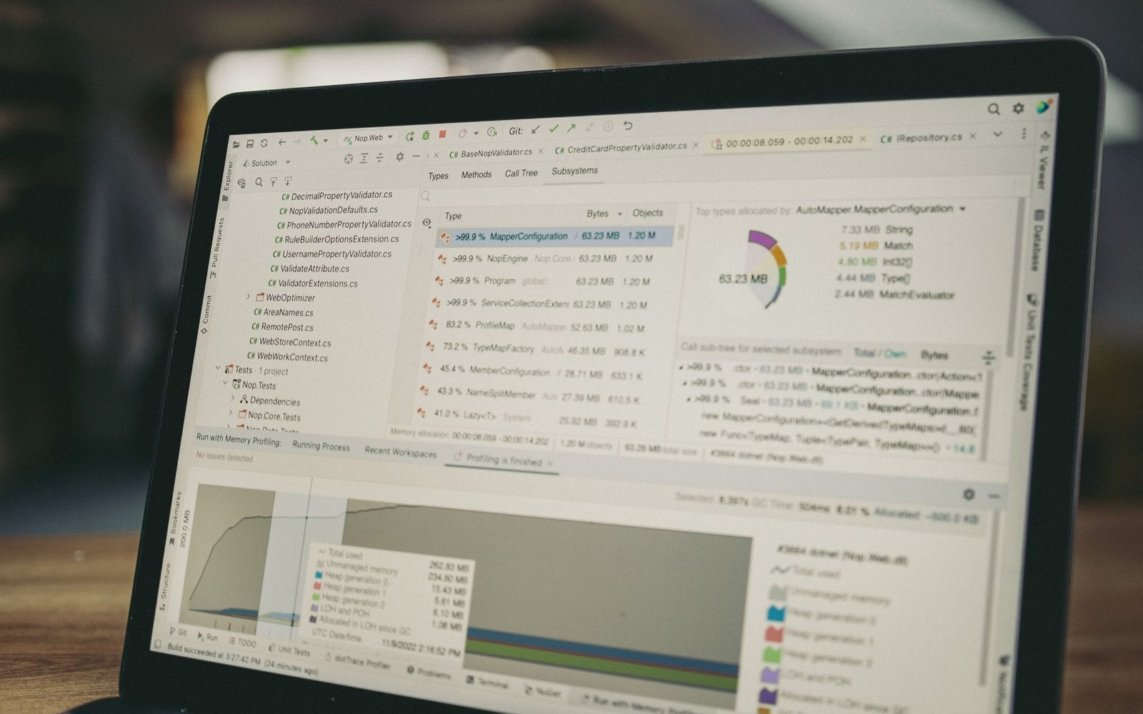 Laptop screen showing code profiling software with memory allocation charts and file structure