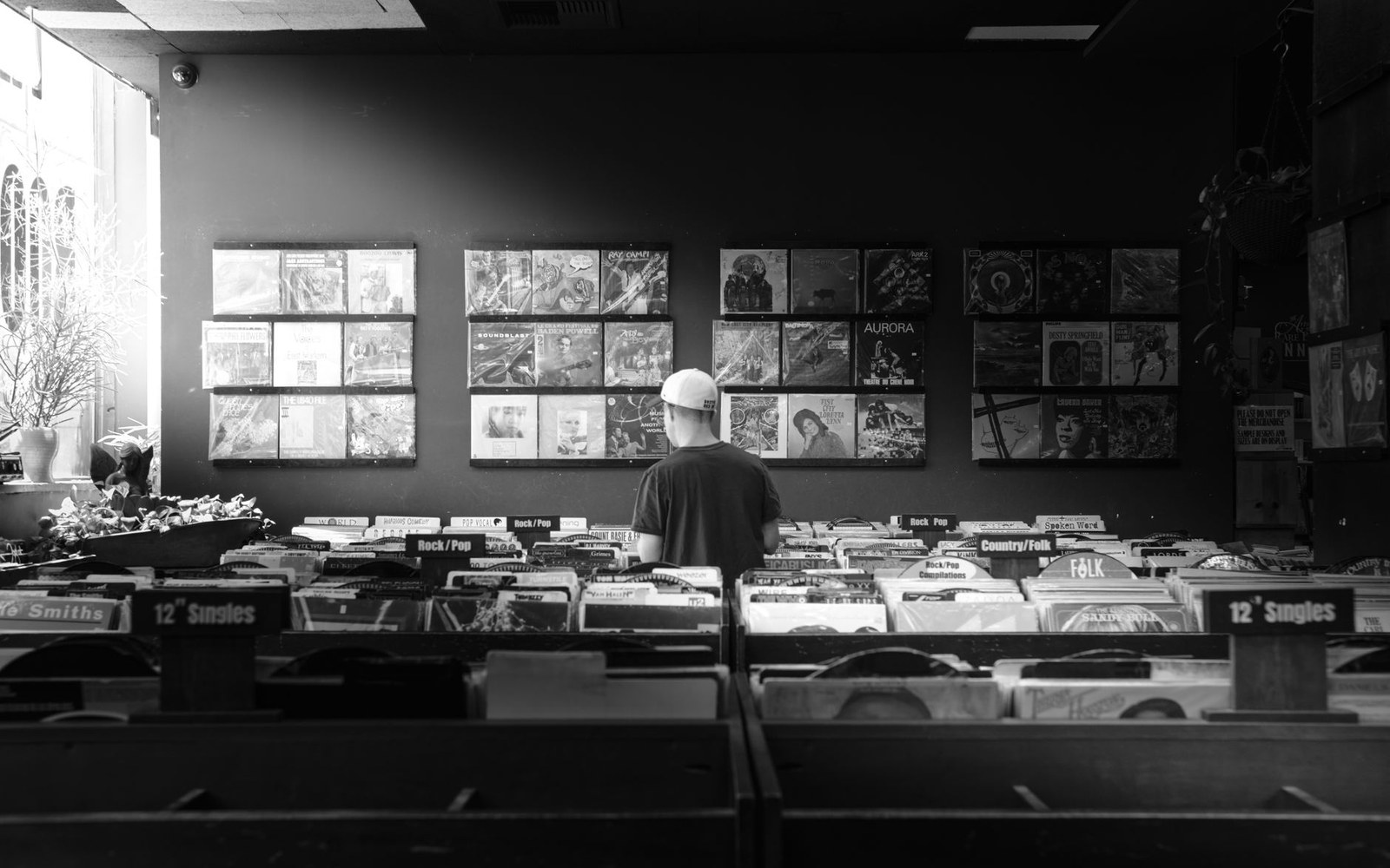 A man browses vinyl records among crates and album displays in a record store