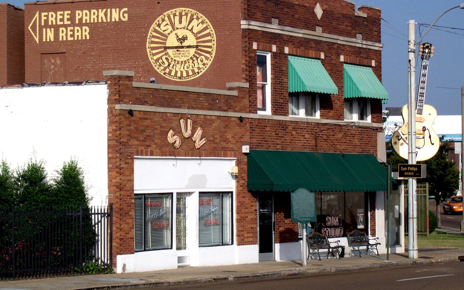 Brick storefront of Sun Studio with green awnings, rooftop logo, and street-side benches