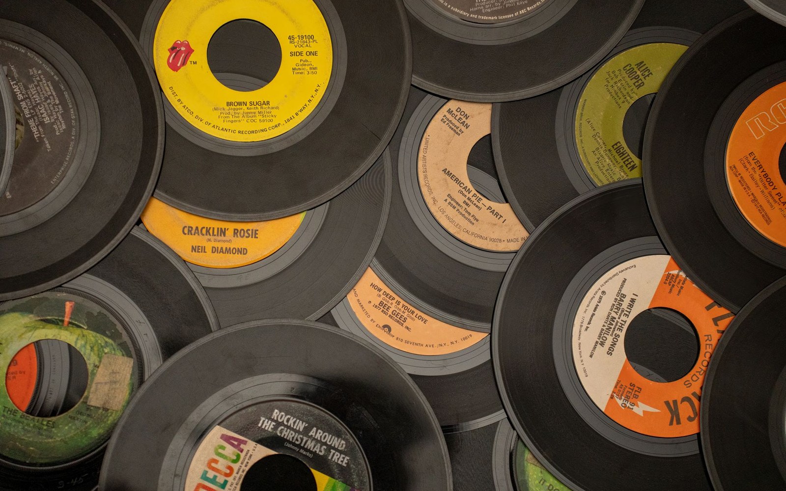 A pile of overlapping vinyl 45 rpm records with labels from various classic artists
