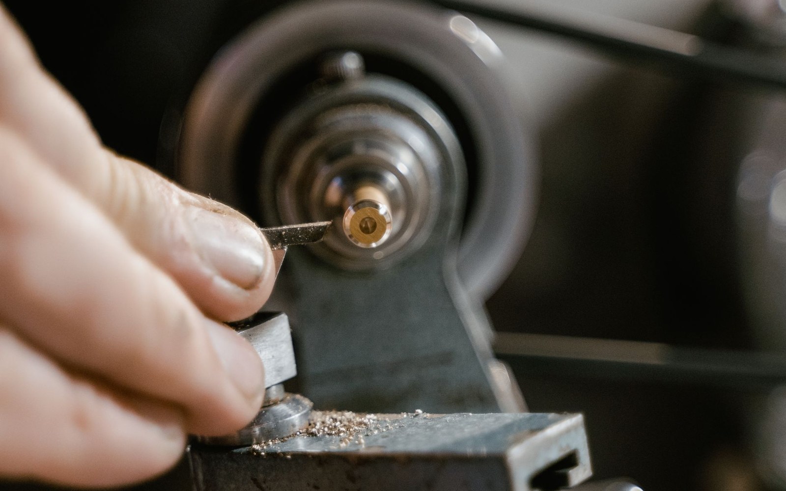 An adult engineer at a lacquer-cutting lathe in a pressing plant, hands visible on the controls